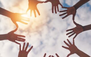 Hands in a circle with the sky in the background, portraying connection