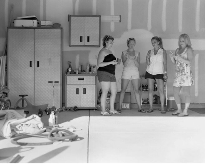 Black and White Image of Women chatting in a garage on their imaginary phones