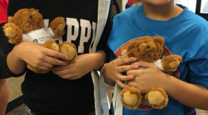 Children holding Prowers Medical Center teddy bear promotional products featuring the new logo